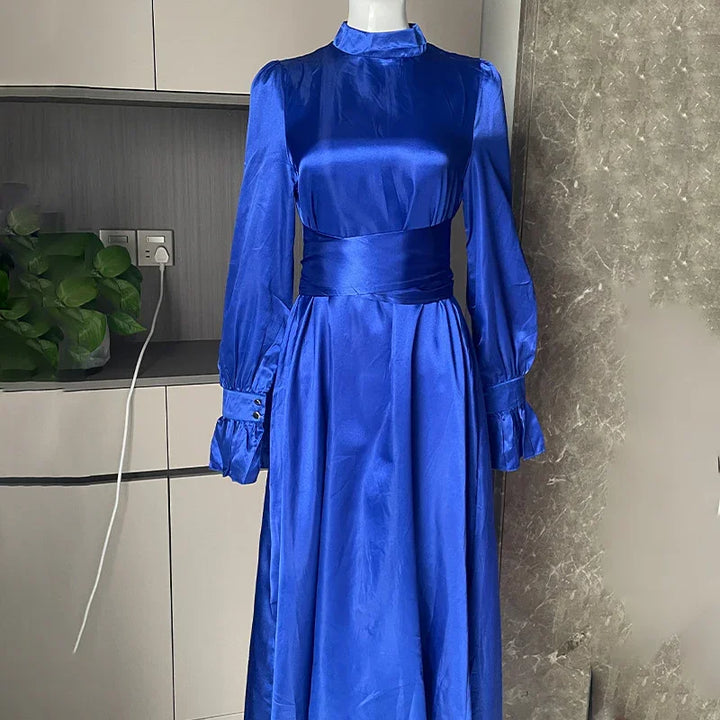 Elegant royal blue satin long sleeve dress with high collar and wide waist sash on mannequin