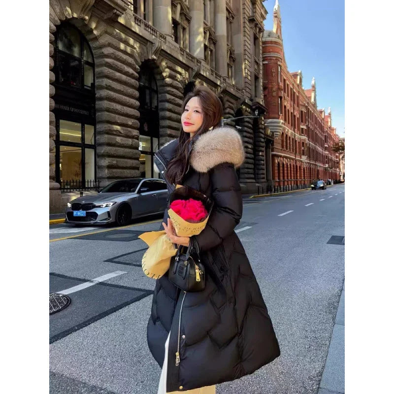 Woman in long black winter coat with fur collar holding red roses and black handbag on city street