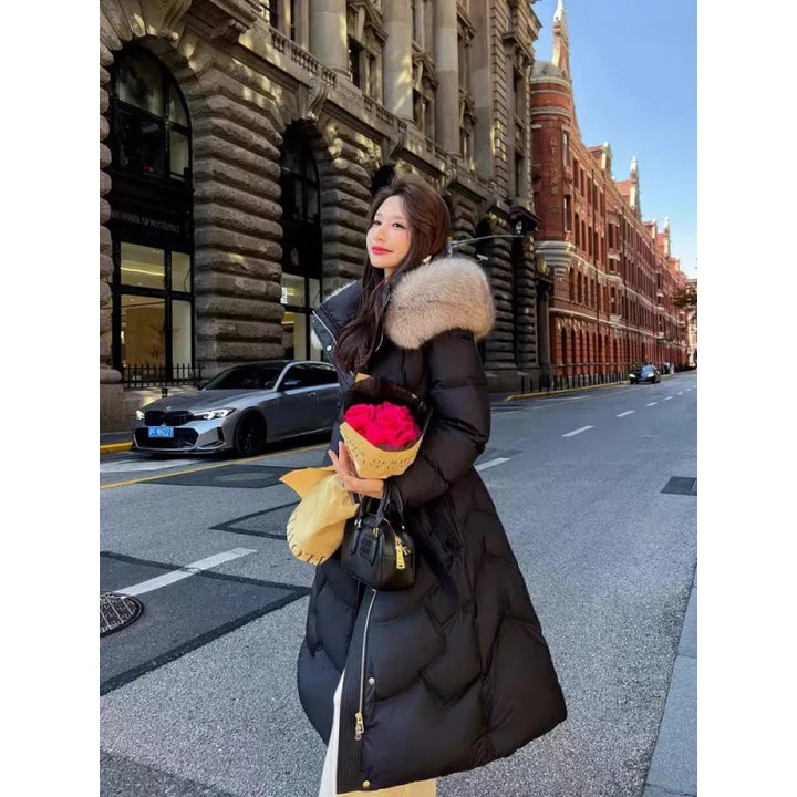 Woman in long black winter coat with fur collar holding red roses and black handbag on city street