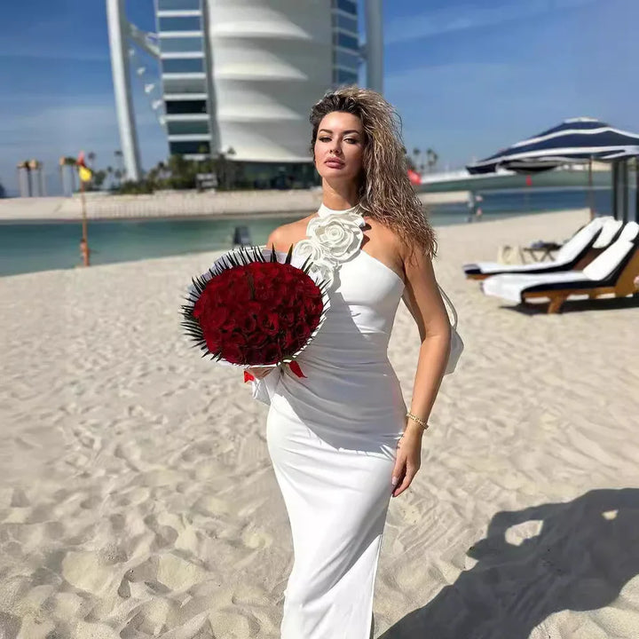 Woman in white dress holding red rose bouquet on Dubai beach near Burj Al Arab hotel
