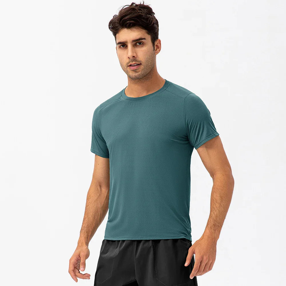 Man wearing teal athletic t-shirt and black shorts, studio background, activewear