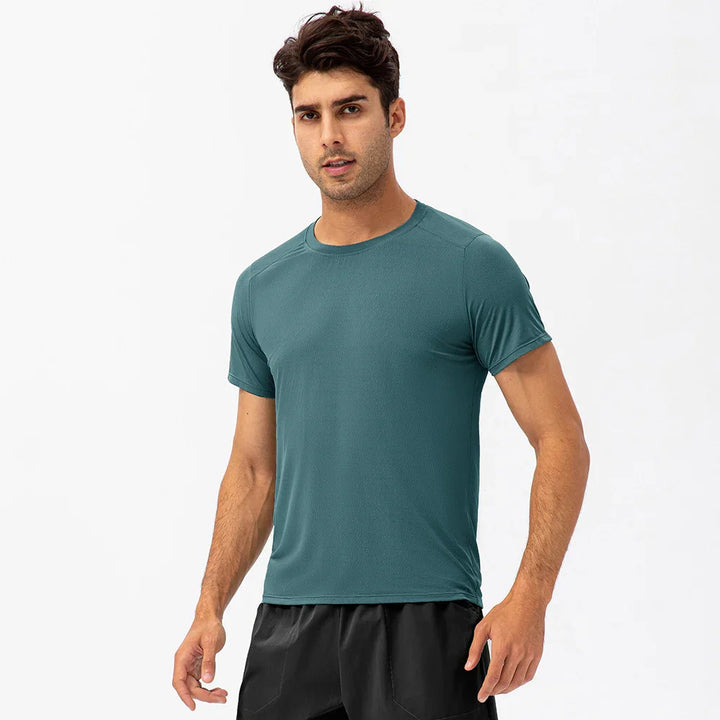 Man wearing teal athletic t-shirt and black shorts, studio background, activewear