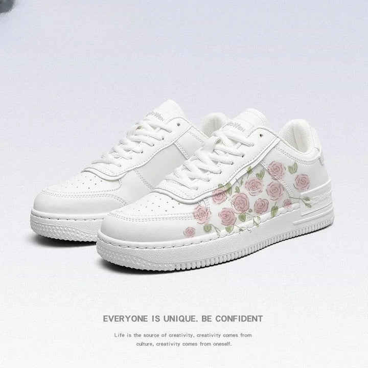 White sneakers with delicate pink rose and green leaf pattern on the side, minimalist background