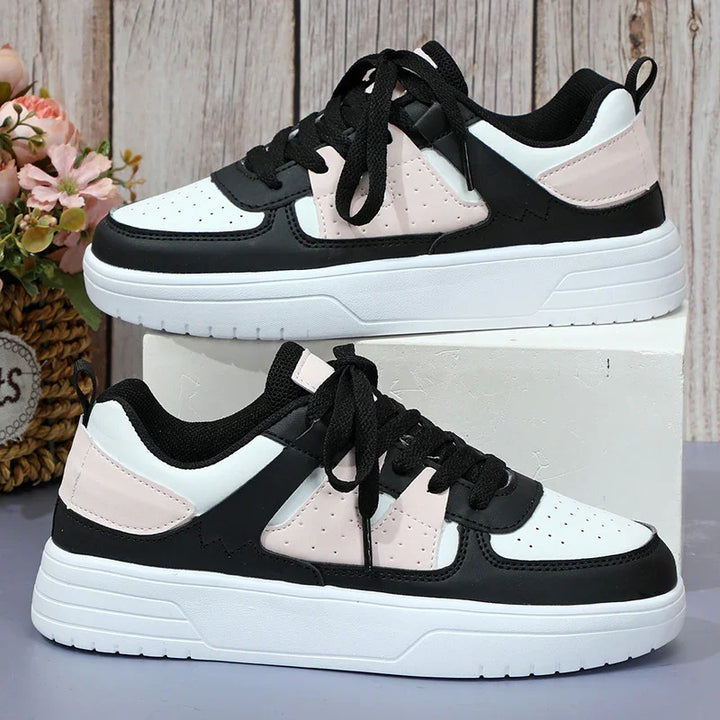 Black, white, and pale pink casual sneakers with black laces displayed on a white box