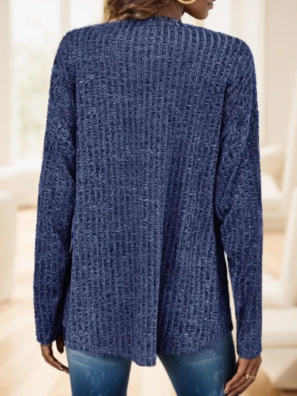 Woman wearing a textured navy blue knit sweater with long sleeves, shown from back