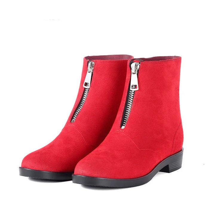Pair of red suede ankle boots with front silver zipper and black low heel on white background