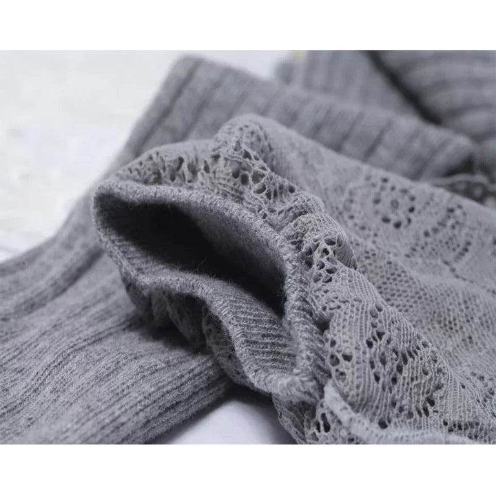 Close-up of soft gray ribbed and lace knit fabric, highlighting intricate patterns and texture