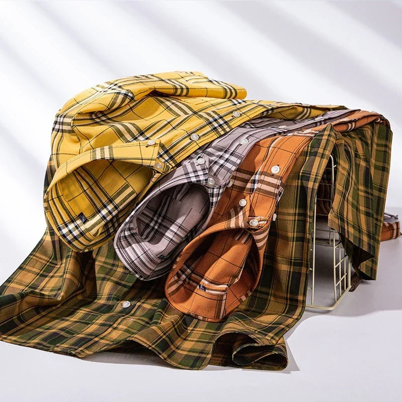 Stack of folded plaid button-up shirts in yellow, gray, orange, and green on white background