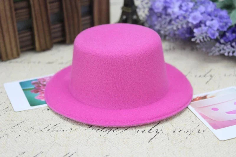 Bright pink felt hat on vintage script surface with blurred purple flowers and photos