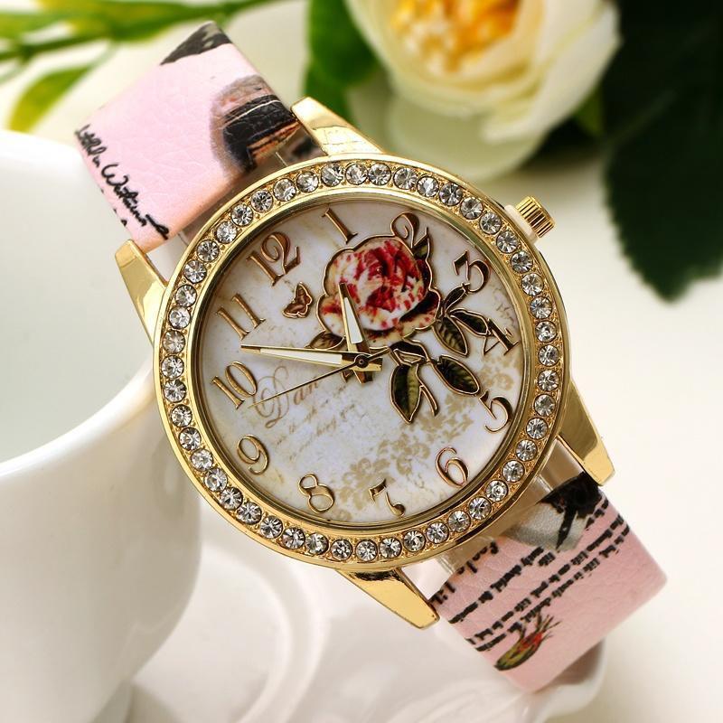 Elegant gold wristwatch with crystal-studded bezel, floral dial design, and pink printed leather strap