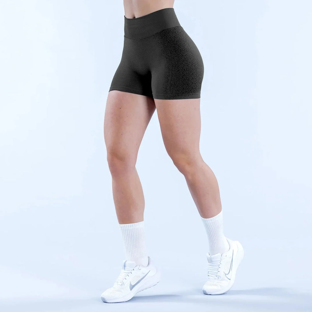 Woman wearing black high-waisted gym shorts, white socks, and white athletic sneakers