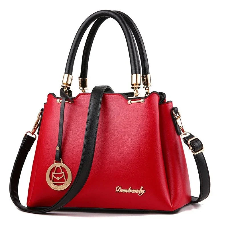 Red leather handbag with black handles, gold hardware, and detachable shoulder strap