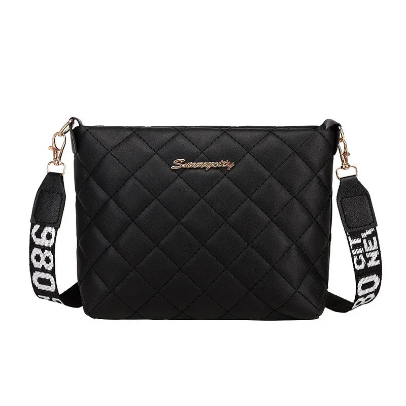 Black quilted crossbody bag with gold hardware and adjustable strap featuring white text