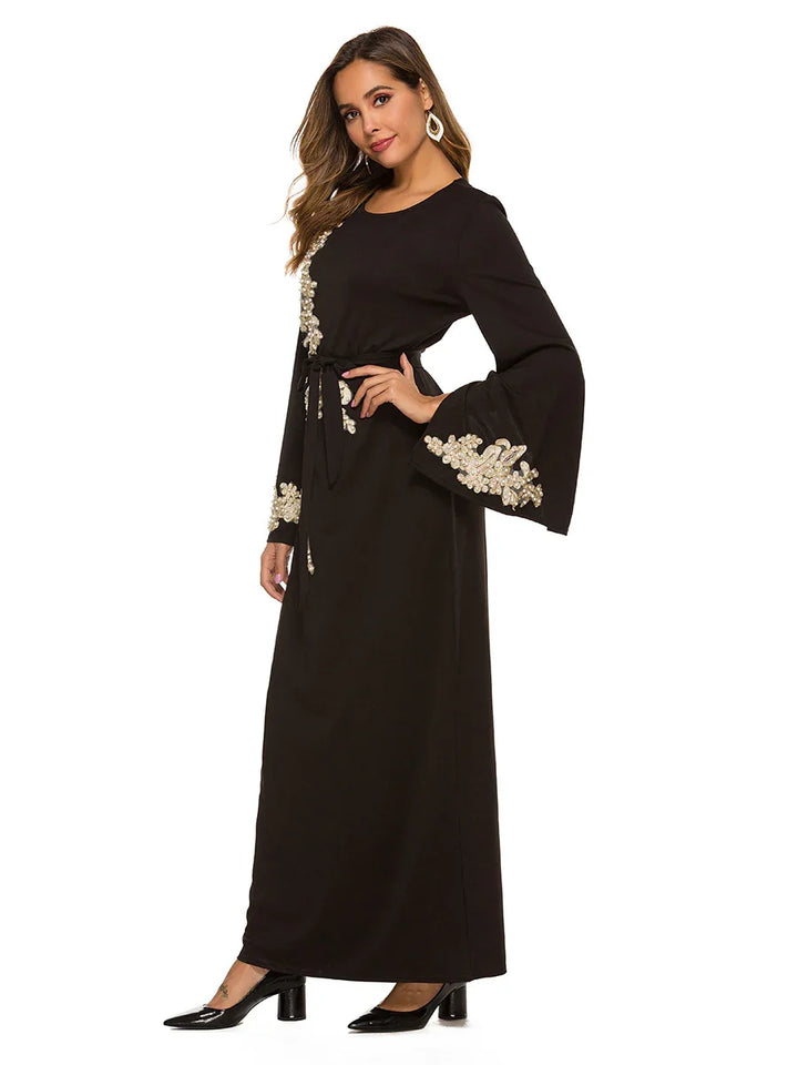 Woman wearing a black long sleeve maxi dress with floral embroidery and flared sleeves