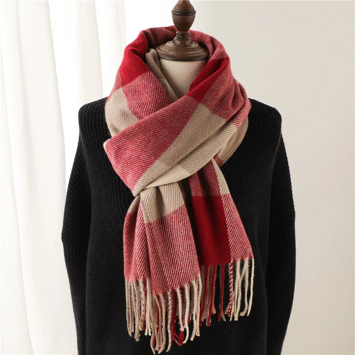 Red and beige plaid scarf with fringe on black knit sweater, displayed on wooden mannequin