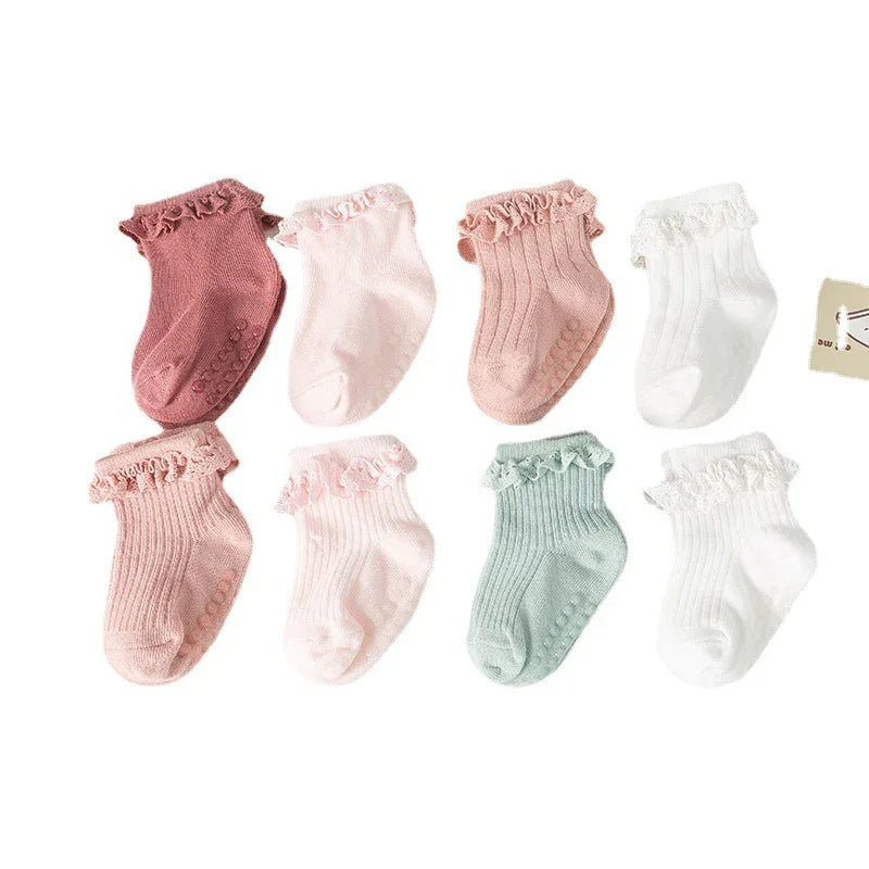 Set of eight pastel-colored baby socks with ruffle trims and non-slip grips in pink, white, and green