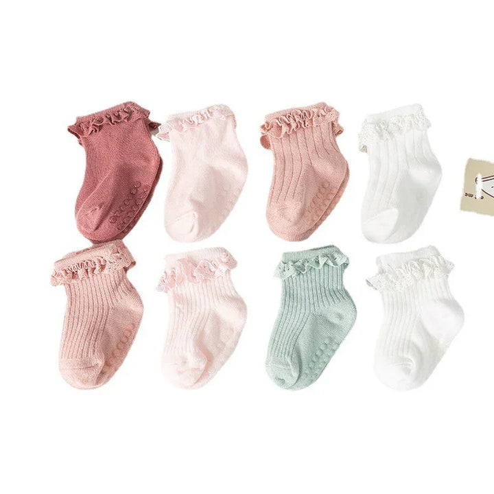 Set of eight pastel-colored baby socks with ruffle trims and non-slip grips in pink, white, and green