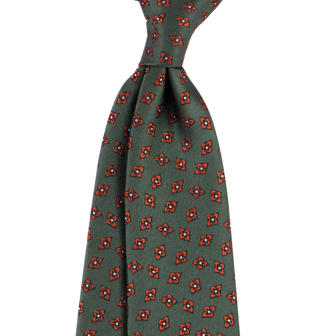 Green silk necktie with red floral and geometric pattern, tied in a classic knot on white background