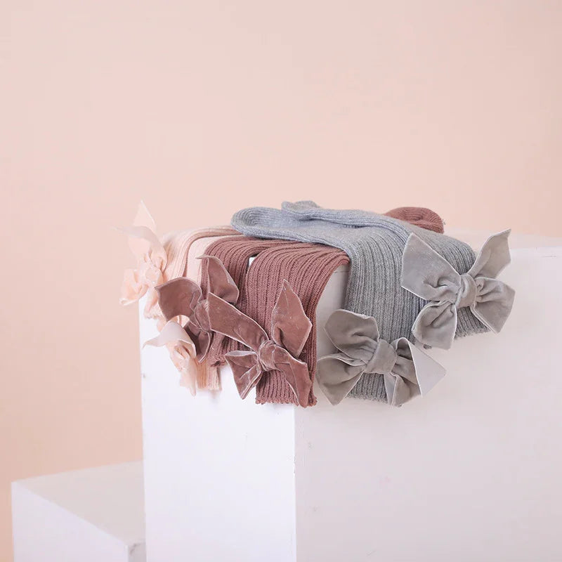 Soft knit baby headbands in pink, brown, and gray with large velvet bows displayed on white blocks