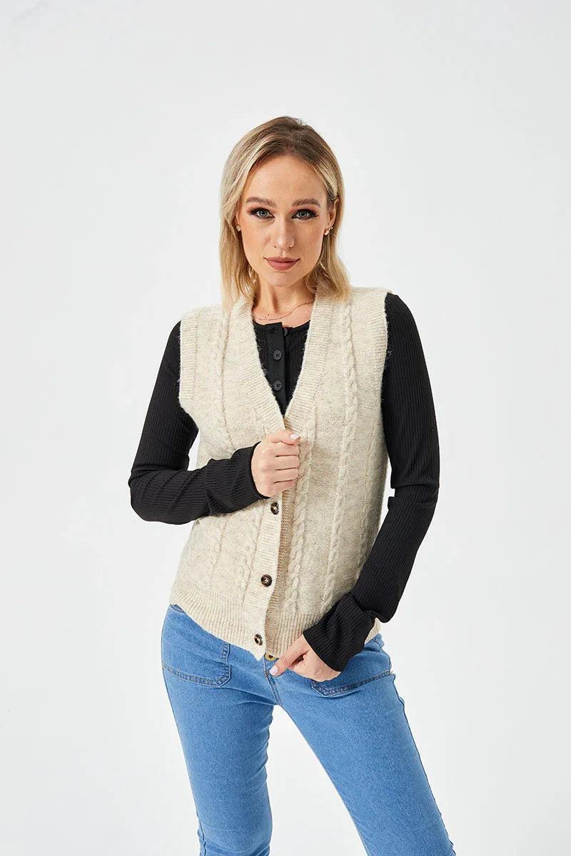 Blonde woman wearing beige cable knit buttoned vest over black long sleeve top and blue jeans