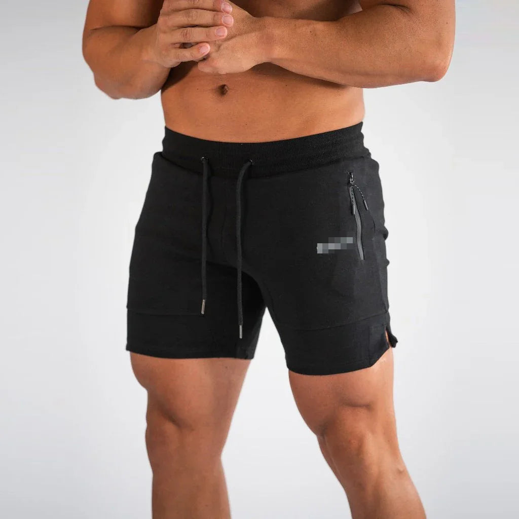 Man wearing black athletic shorts with zippered pocket and drawstring waist on plain background