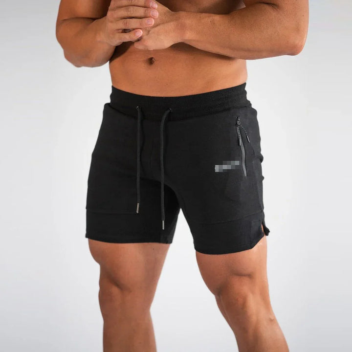 Man wearing black athletic shorts with zippered pocket and drawstring waist on plain background