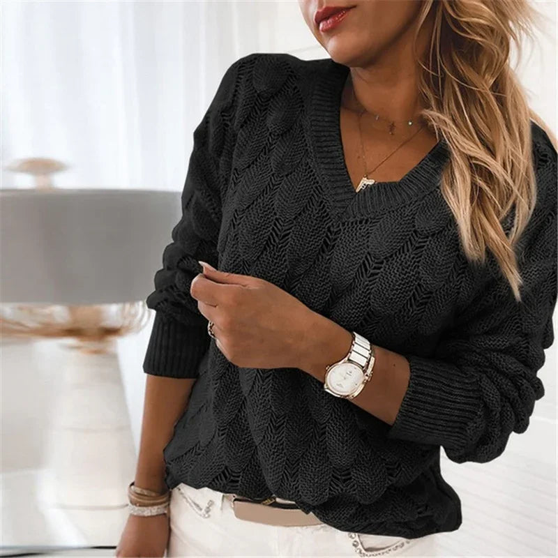 Woman wearing a black cable knit V-neck sweater with white pants and a white watch