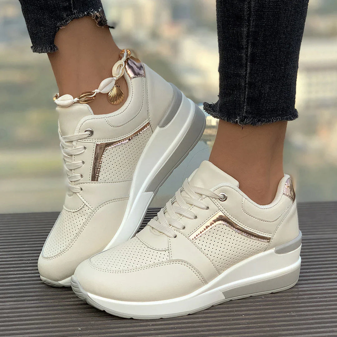White wedge sneakers with rose gold accents worn with black frayed hem jeans and shell anklet