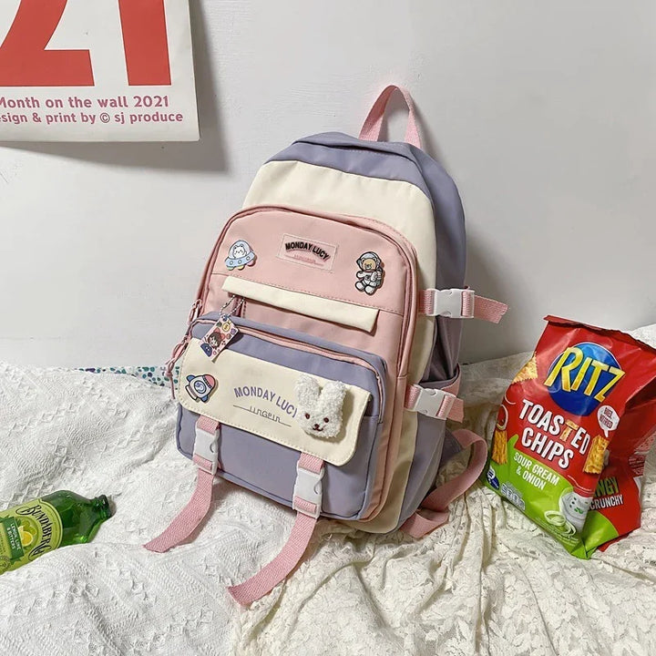 Pastel pink and lavender Monday Lucy backpack with cute patches next to Ritz sour cream & onion chips