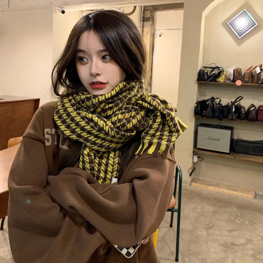 Young woman indoors wearing a brown oversized sweatshirt and yellow-checkered scarf, with shelves of handbags in background