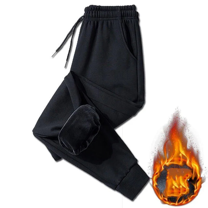 Black fleece-lined jogger pants with elastic waistband and drawstrings, shown with fire graphic indicating warmth
