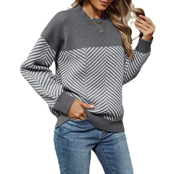 Woman wearing gray and white striped knit sweater with ribbed cuffs and hem, paired with blue jeans