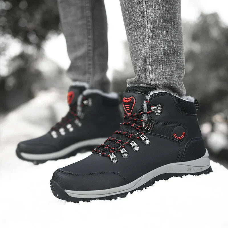 Black and gray outdoor hiking boots with red accents worn with gray pants on snowy ground