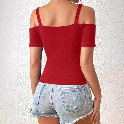 Woman wearing red off-shoulder top with straps and light denim distressed shorts against white background