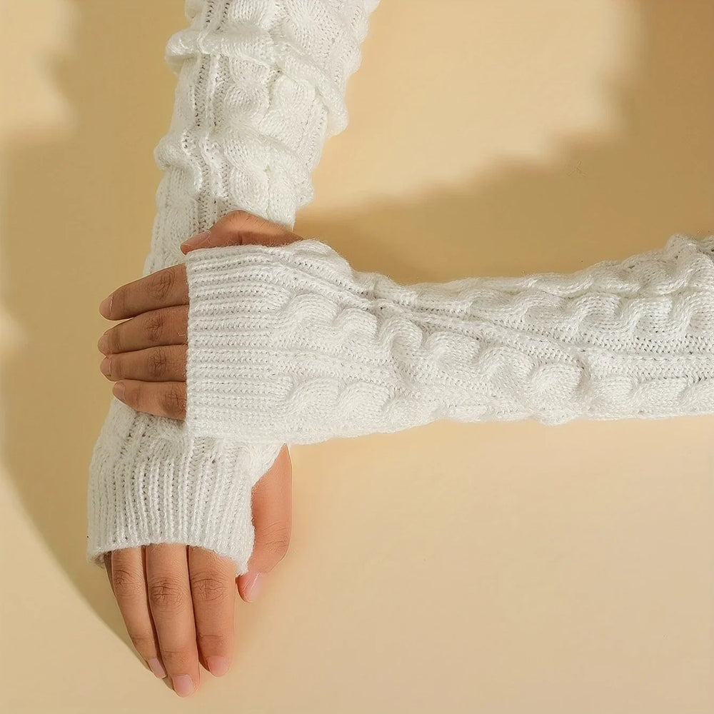 Hands wearing white cable knit fingerless gloves on beige background