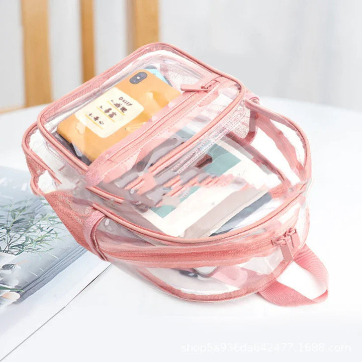 Pink transparent backpack with phone and books inside on white table