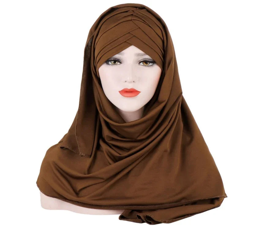 Mannequin wearing brown pleated hijab with draped fabric over shoulders against white background