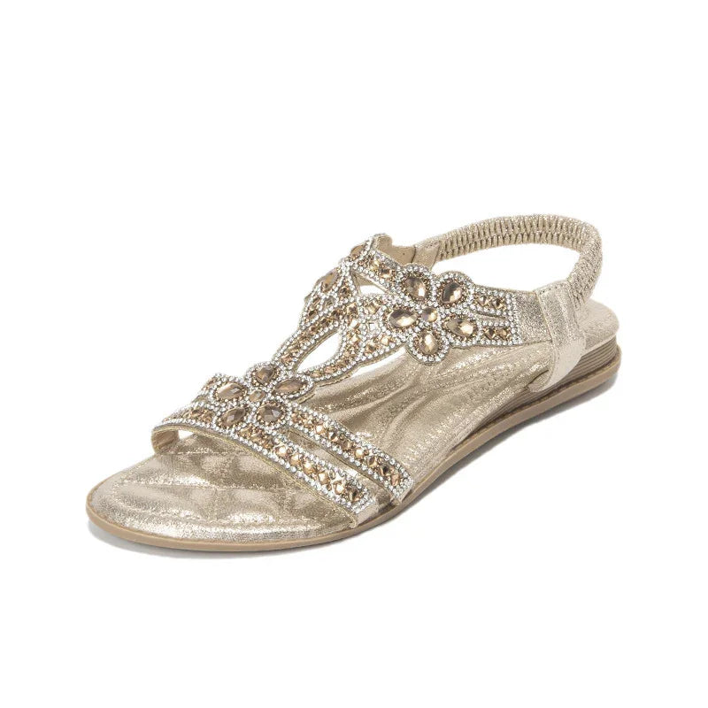 Gold women's flat sandal with elastic back strap and decorative rhinestone floral design