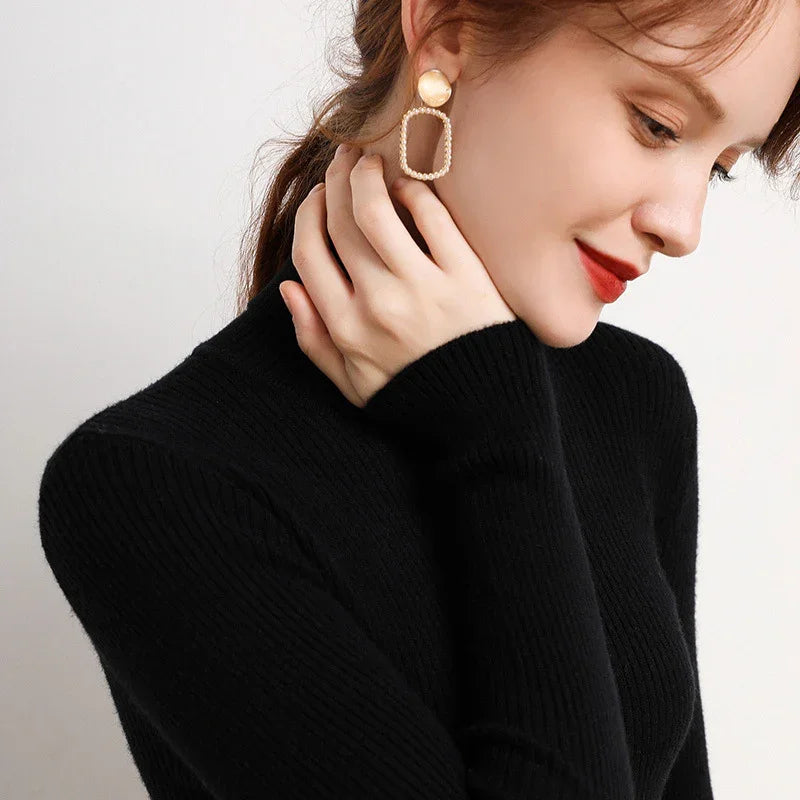 Close-up of a woman wearing a black sweater and stylish gold pearl rectangular hoop earrings