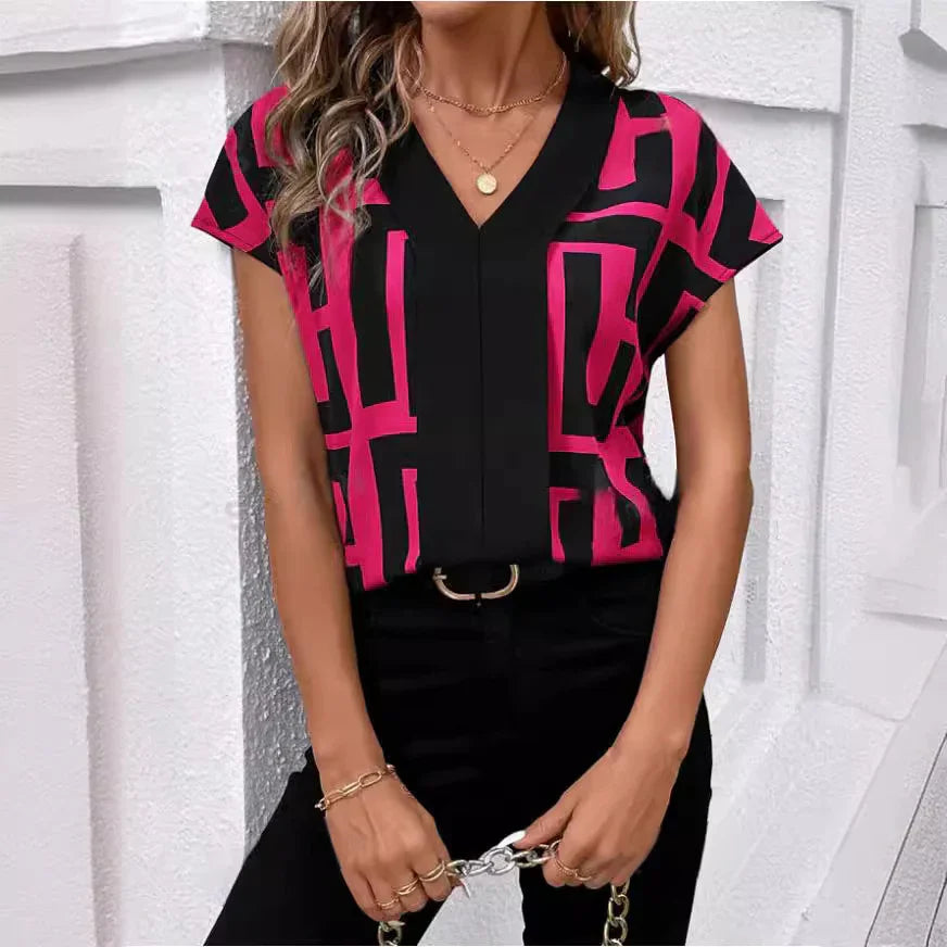 Woman wearing black and pink geometric print V-neck blouse with short sleeves, paired with black pants