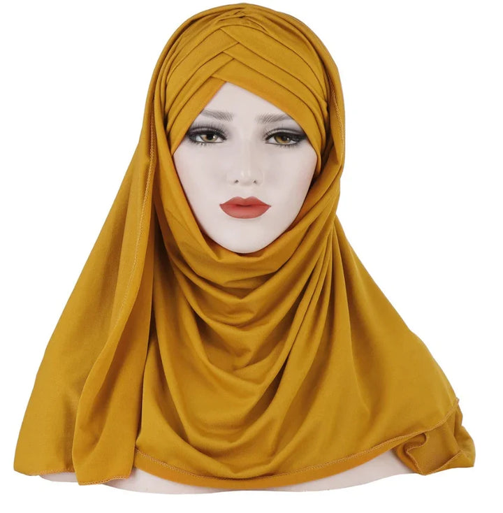 Mannequin head wearing mustard yellow pleated hijab with draped fabric style