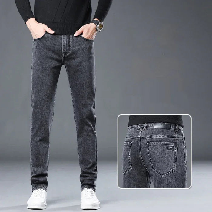 Men's black slim fit jeans with white sneakers on grey background, close-up of back pockets