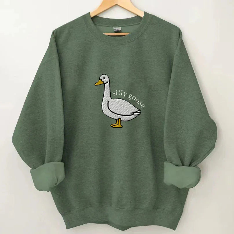 Green sweatshirt with rolled sleeves featuring an embroidered white goose and the text silly goose
