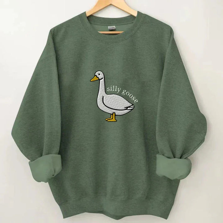 Green sweatshirt with rolled sleeves featuring an embroidered white goose and the text silly goose
