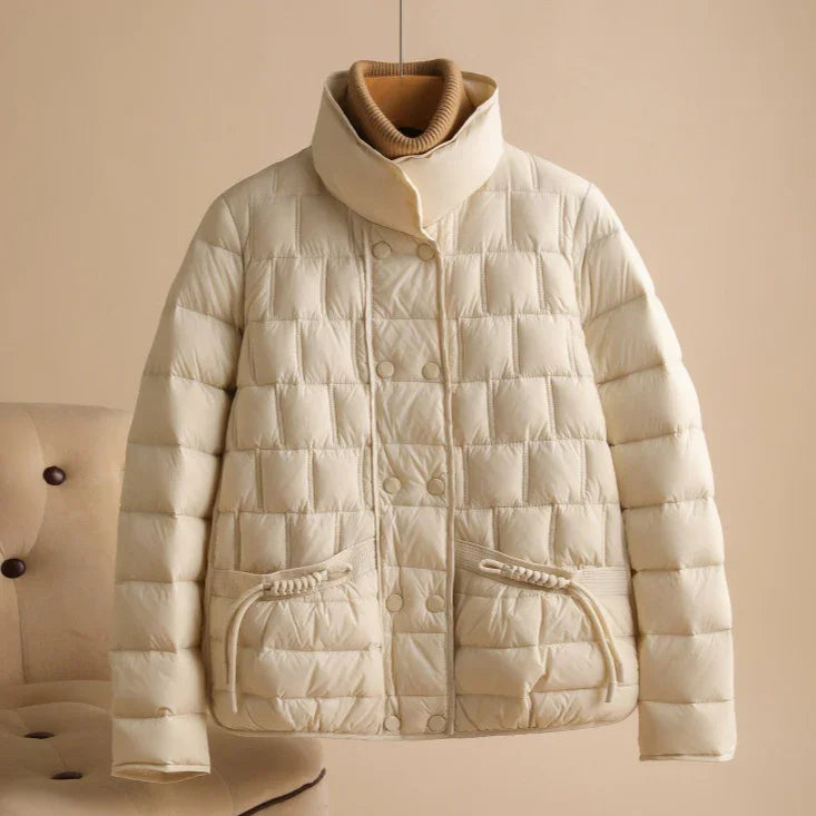 Beige quilted padded jacket with button closure and front pockets displayed on beige background
