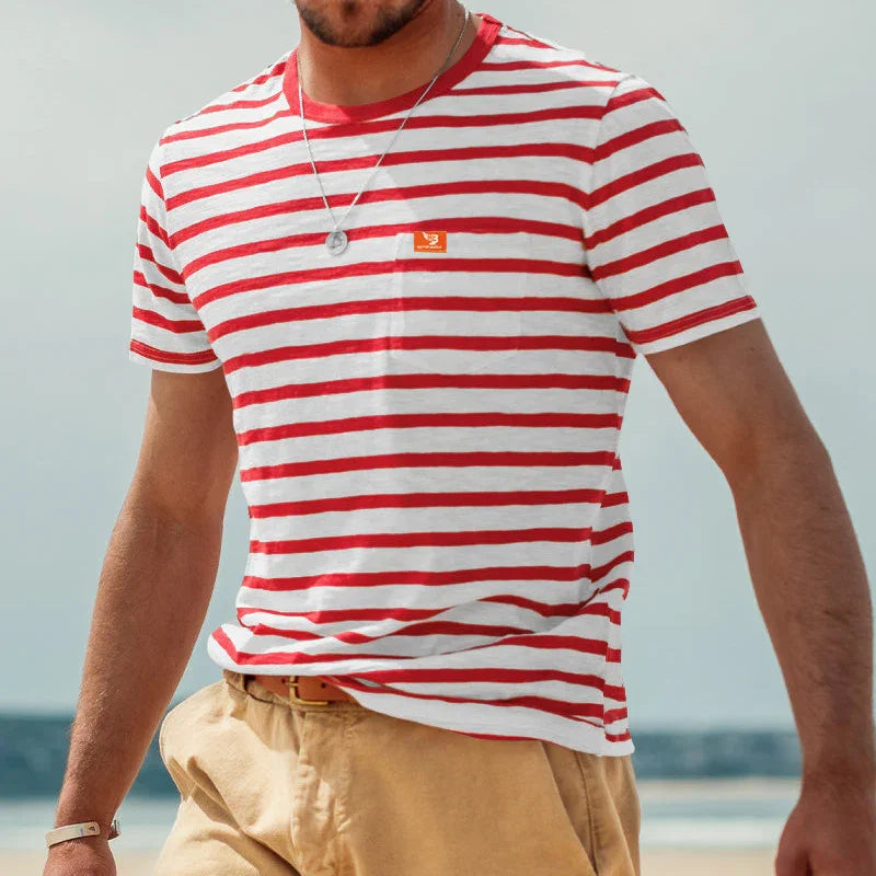 Man wearing red and white striped t-shirt and beige pants at the beach on a sunny day