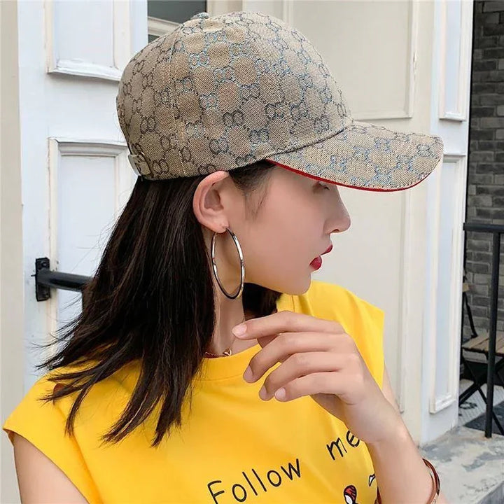 Woman wearing beige monogram Gucci baseball cap and yellow sleeveless top with hoop earrings