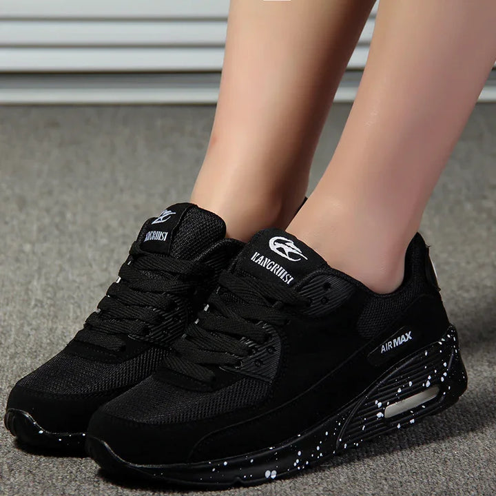 Black KANGCHUASI Air Max sneakers with white speckled soles worn on carpeted floor