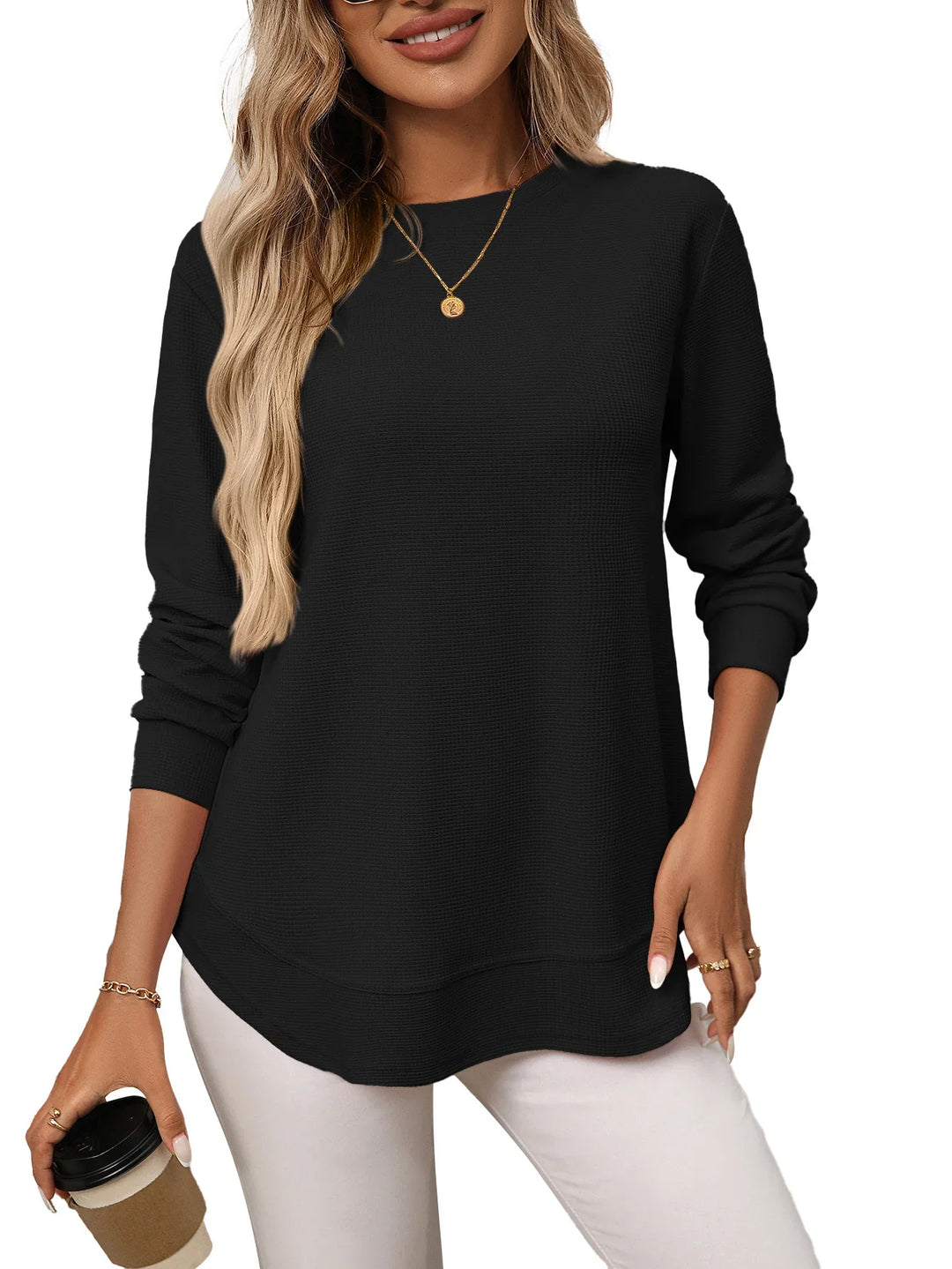Woman wearing black long sleeve casual top with textured fabric holding coffee cup
