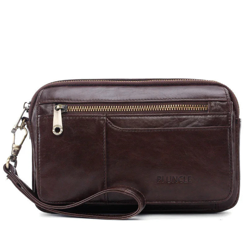 Dark brown leather wristlet clutch with front zipper pocket and detachable strap on white background